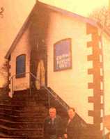 Two members of the Orange Hall stand at the front of the hall the scorch marks very much in evidence on the door and Orange Hall